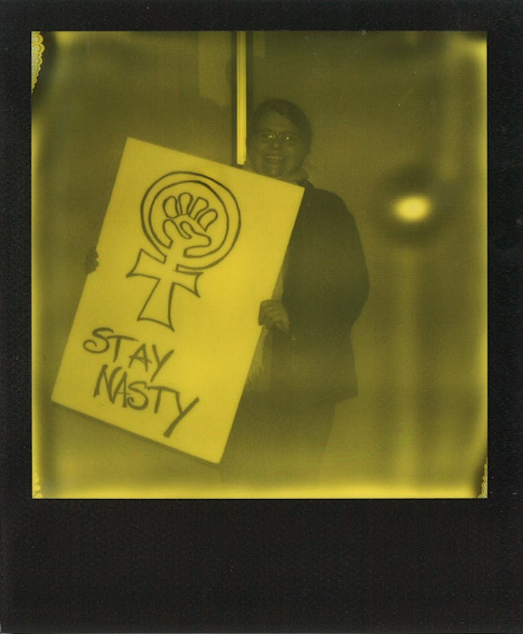 A man holding a poster with "STAY NASTY" text at the Women’s March in NYC