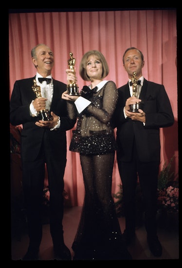 Barbra Streisand posing with her Best Actress Award in sequin see-through bell-bottom pants with a m...