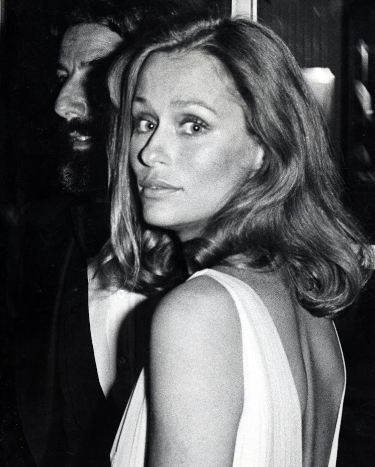 Lauren Hutton in a white dress, with her hair down, looking over her shoulder at the Oscars 