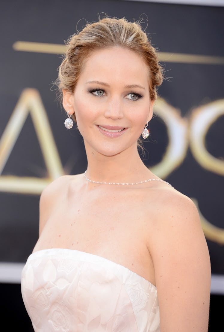 Jennifer Lawrence in a strapless white dress, an up do and dangling white earrings at the Oscars 