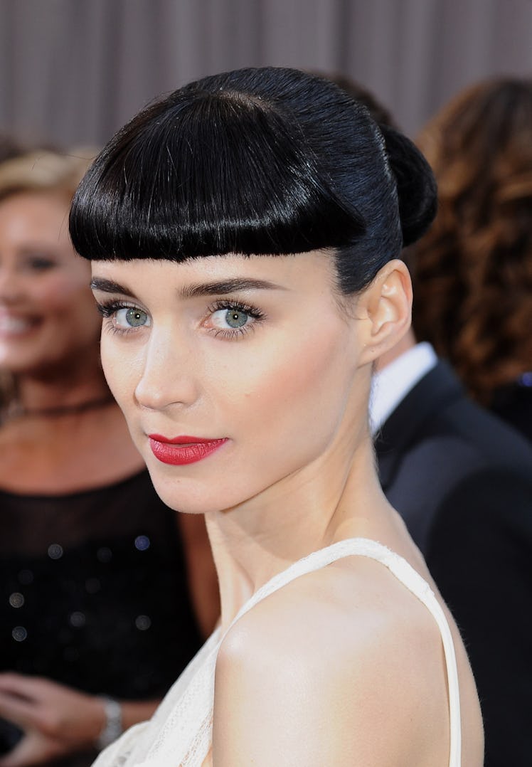 Rooney Mara with short bangs and red lipstick, in a white dress at the Oscars