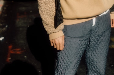 A close-up of a man wearing a beige hoodie and grey pants at Hood by Air Sample Sale Street Style
