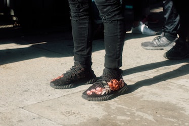 A close-up of a person wearing black sneakers with floral print and black trousers at Hood by Air Sa...