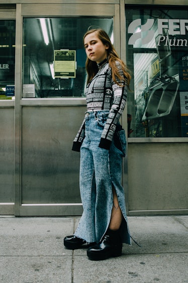 A woman in a black-white printed turtleneck and blue denim jeans with large cut outs on the sides