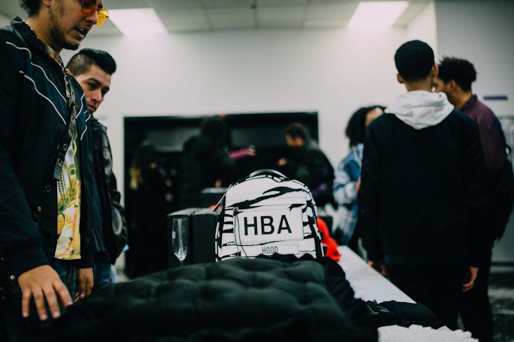 Two men standing and looking at bags on a display at Hood by Air's Sample Sale Street Style