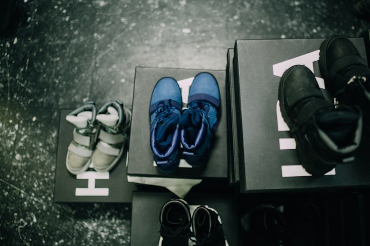 Three pairs of sneakers in a grey, blue and black stacked on black boxes at Air by Hood