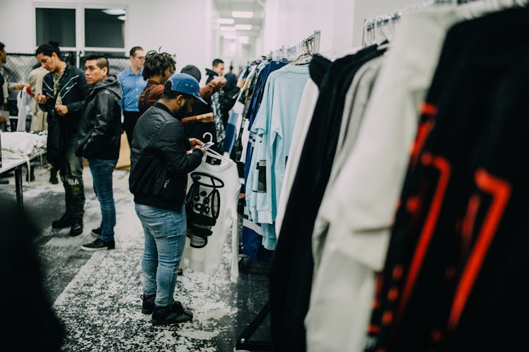 Two people looking at clothes by Hood by Air on a rack and other people standing in the background