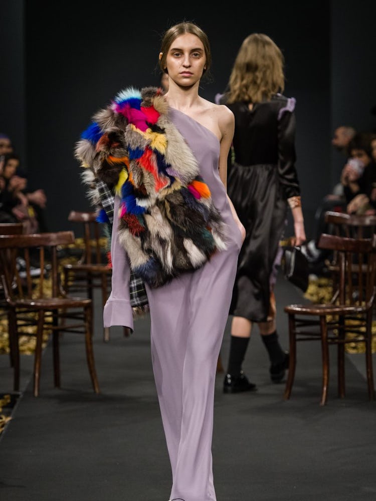 A model in a lilac dress and a multi-colored fur piece element