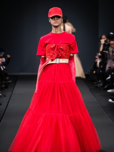 A model in a red shirt and tulle dress on the runway