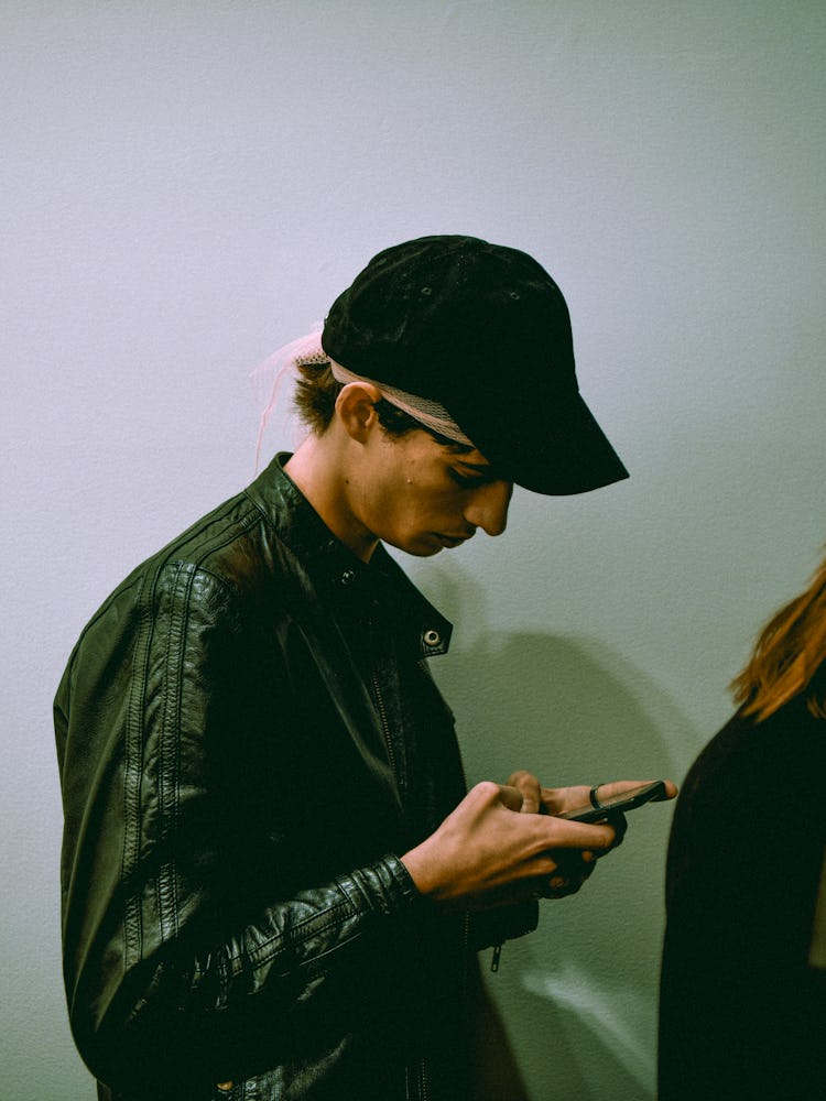 A model looking at his phone backstage before the presentation of Raf Simons A/W ’17 Collection