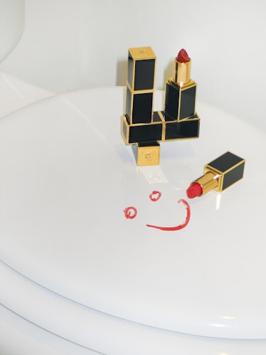 Two opened and two unopened red Tom Ford lipstick an a smiley face on a white surface