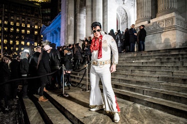An Elvis Presley impersonator standing on the steps in front of the New York Public Library before P...