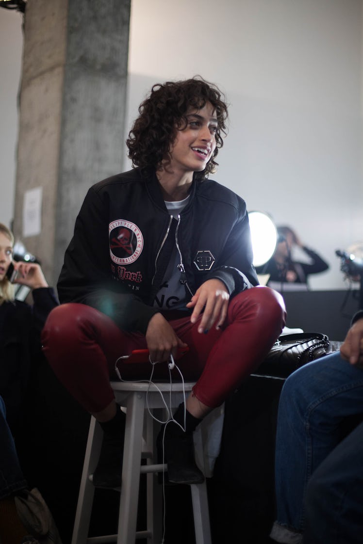 A model backstage at the Zadig & Voltaire show in red leather pants and a varsity jacket, smiling 