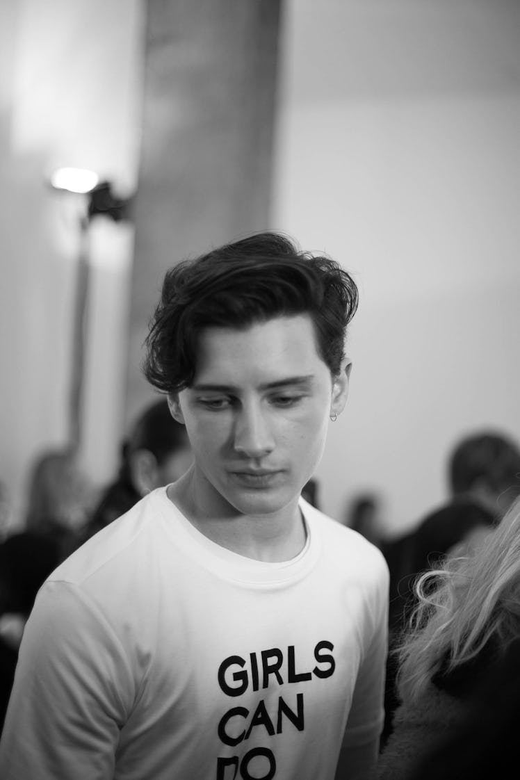 A male model wearing a "girls can do anything" shirt, looking down, backstage at the Zadig & Voltair...