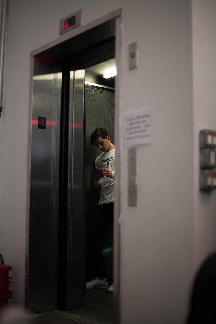 A model using his phone in the elevator backstage at the Zadig & Voltaire Fall 2017 show 