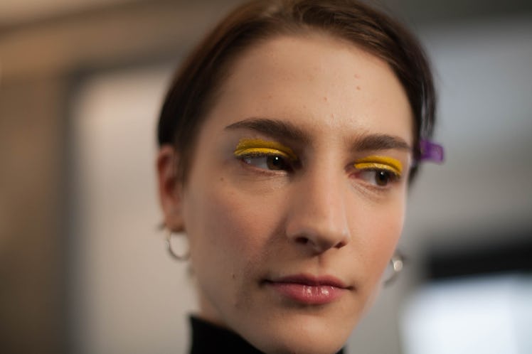 A closeup of a model wearing yellow eyeshadow, looking into the distance backstage at the Zadig & Vo...