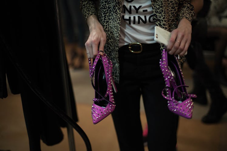 A model holding a pair of purple studded heels backstage at the Zadig & Voltaire Fall 2017 show 