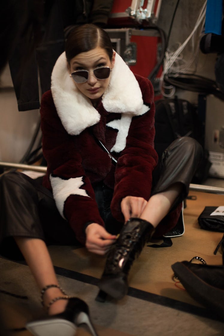 Bella Hadid backstage at Zadig & Voltaire Fall 2017 show sitting on the floor and putting on her boo...