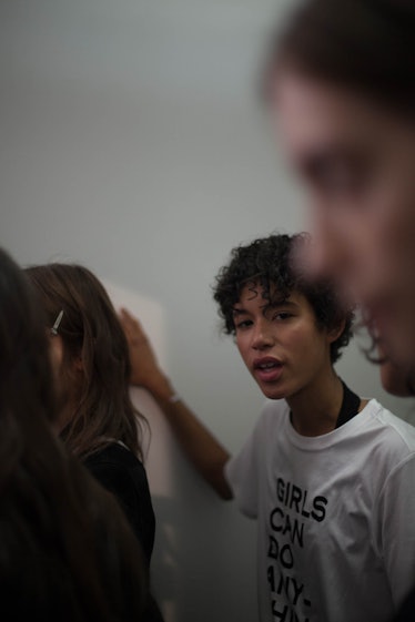 A closeup of a model in the lineup backstage at the show, leaning their hand against the wall 