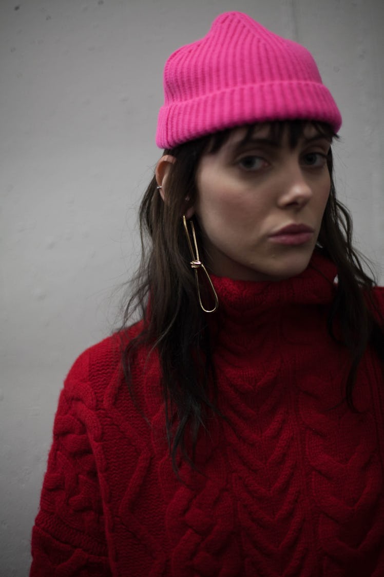 A model backstage at the Zadig & Voltaire Fall 2017 show in a red turtleneck sweater and a pink hat 