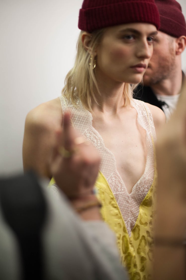 A model in a yellow top with white lace and a maroon beanie backstage at the Zadig & Voltaire show 