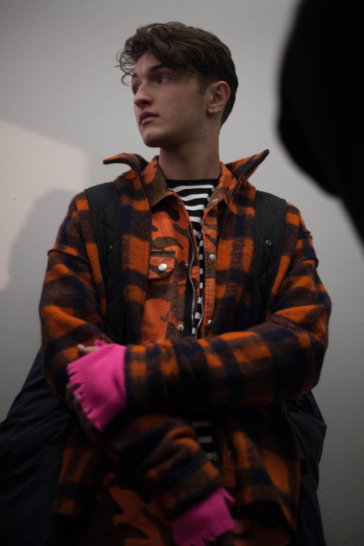 A model in an orange plaid jacket and striped black and white shirt backstage at the Zadig & Voltair...