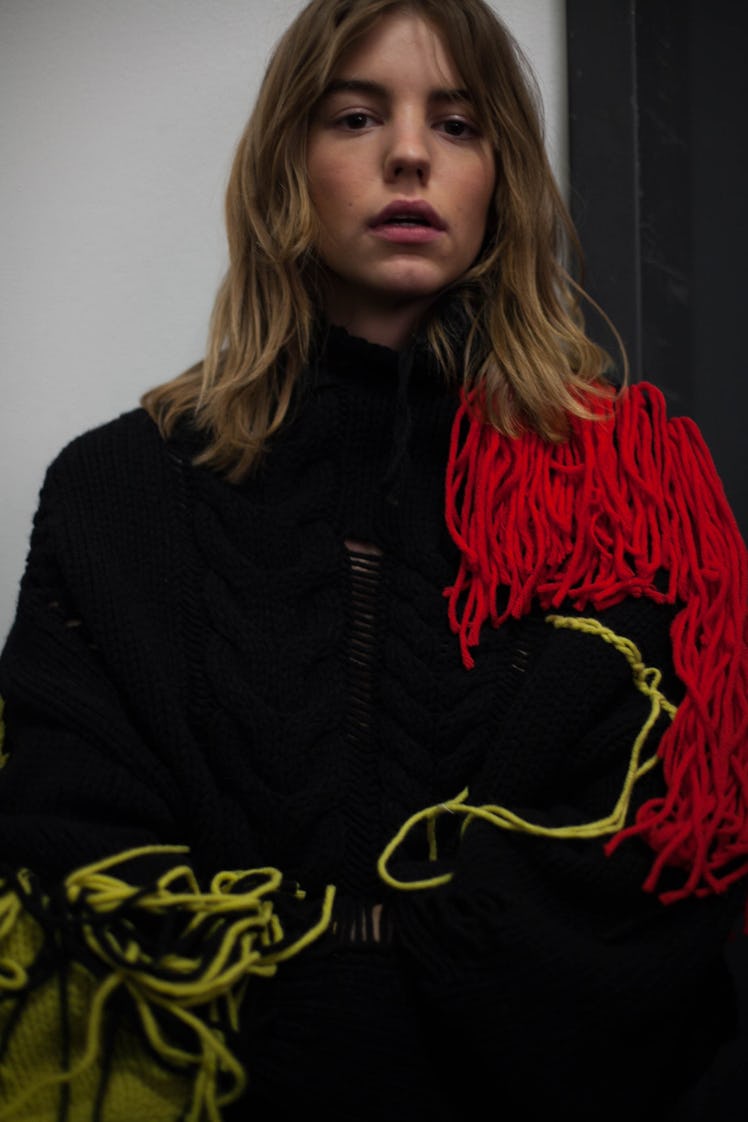 A model backstage at the Zadig & Voltaire show in a black jacket with yellow and red fringe 