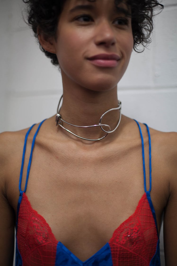 A model in a blue strappy top with red lace and a metal necklace 