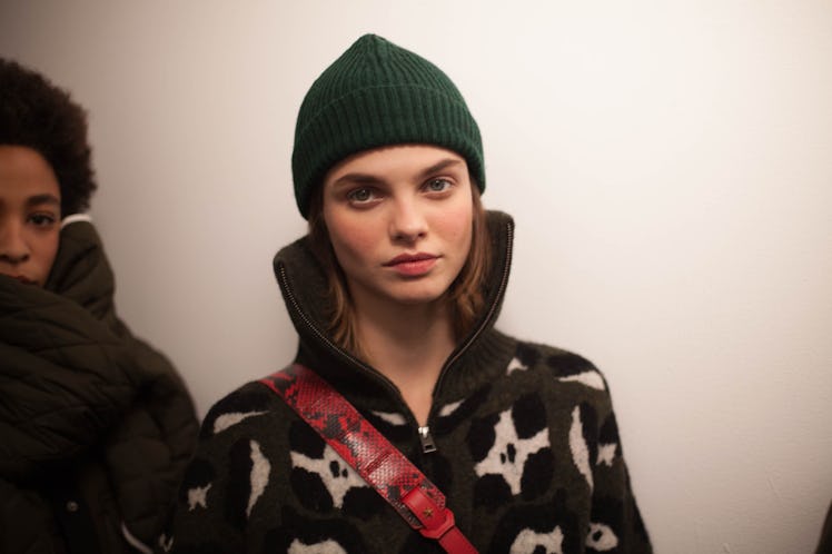 A model in a black fleece jacket and a green beanie looking at the camera 