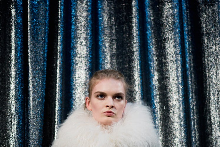 A close-up portrait of a model with a white fur collar backstage at Monse Fall 2017