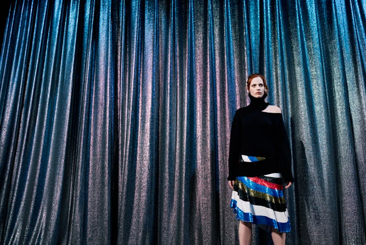 A model in a black top and black-red-blue-white skirt backstage at Monse Fall 2017