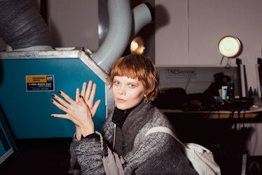 A model posing with her hands clapping in a grey sweater backstage at Monse Fall 2017