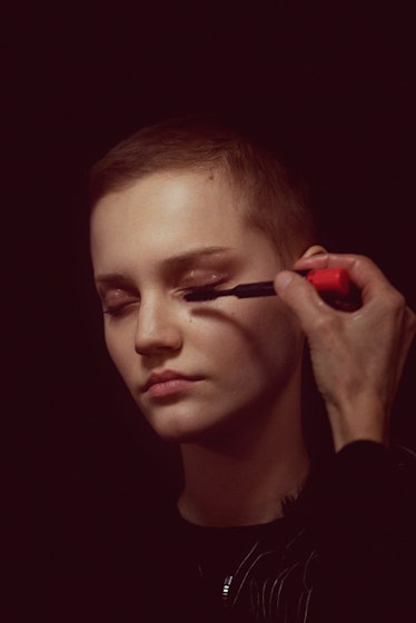 A close-up portrait of a model getting her makeup done by a makeup artist backstage at Monse Fall 20...