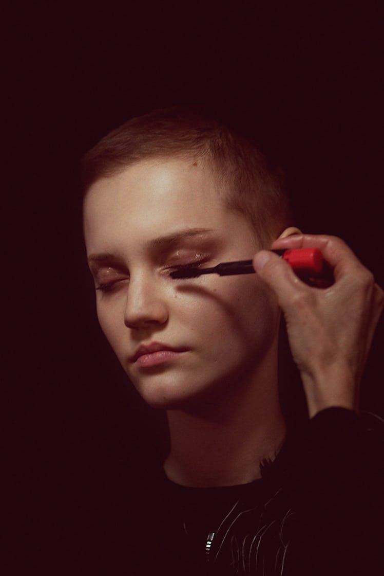 A close-up portrait of a model getting her makeup done by a makeup artist backstage at Monse Fall 20...