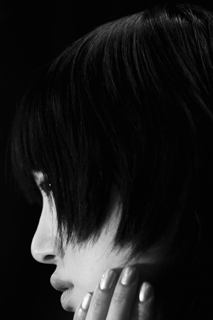 A close-up portrait of a model leaning her hand against her jawline backstage at Oscar de la Renta F...