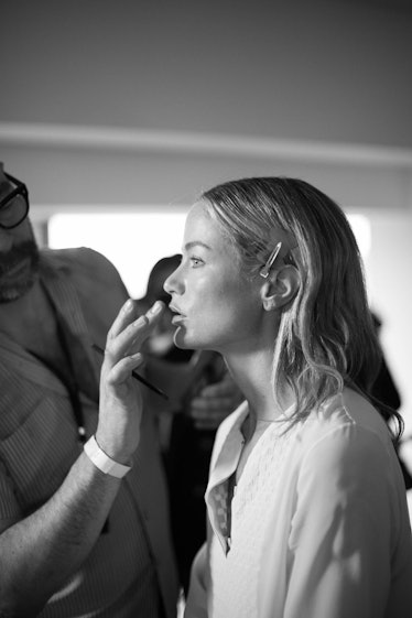 A makeup artist checking the face makeup of a blonde female model 