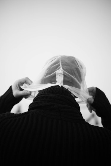 A man putting a white mask cap on his head