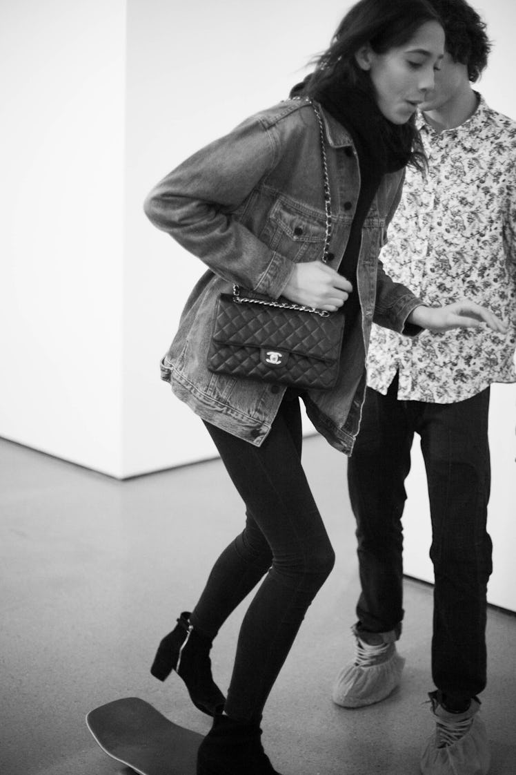 A black-haired woman walking in a light-blue Texas jacket and black leggings while carrying a black ...