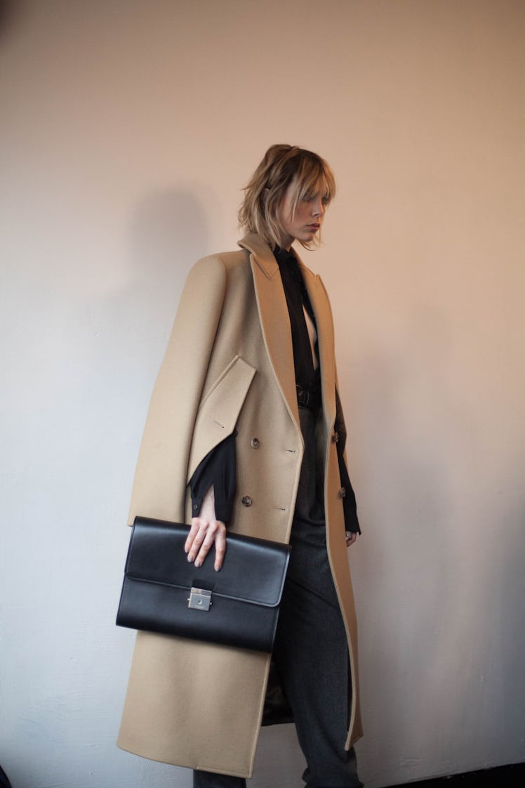 A woman wearing a light brown coat over a black shirt and pants