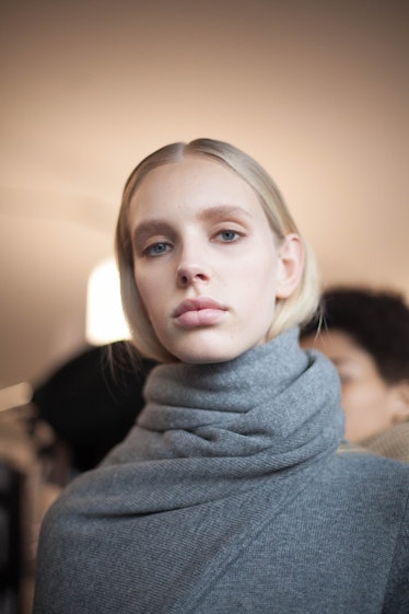 A blonde woman posing in a grey sweater