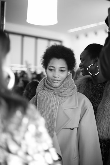 A curly and black-haired female model wearing a grey coat