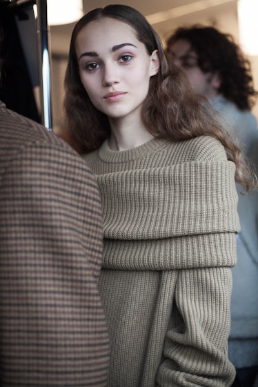 A young lady posing in an olive green sweater