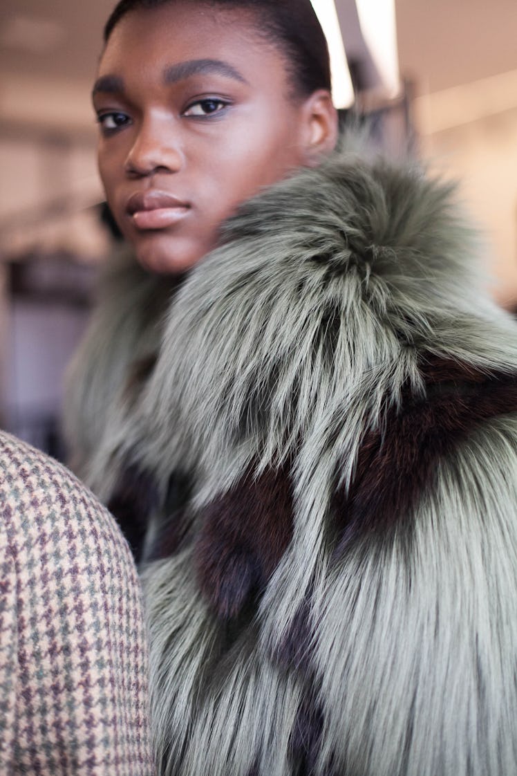 A woman posing in a green and black fur coat