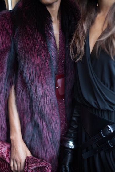 A woman in a dark blue blouse standing next to a woman in a purple fur coat