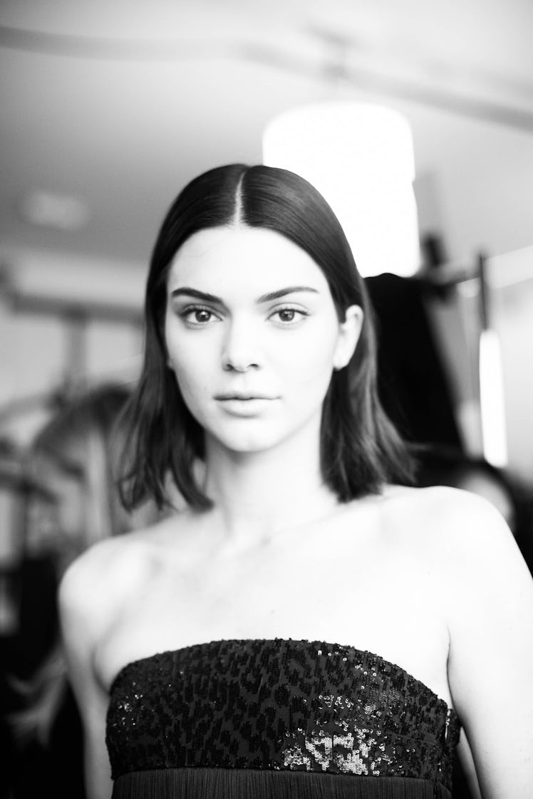 A black-haired female model posing for a photo in a black mini dress