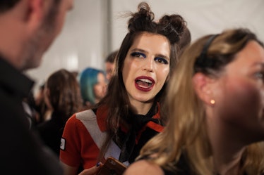 A brunette model in a red-white-black top and a double top knot speaking backstage at Anna Sui Fall ...
