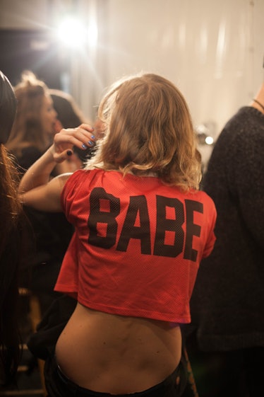 The back of a model dancing in a red shirt with the text babe backstage at Anna Sui Fall 2017