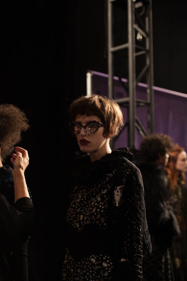 A brunette model with a short bob in a black lace dress backstage at Anna Sui Fall 2017