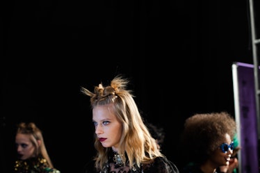 A blonde model with a double top knot backstage at Anna Sui Fall 2017