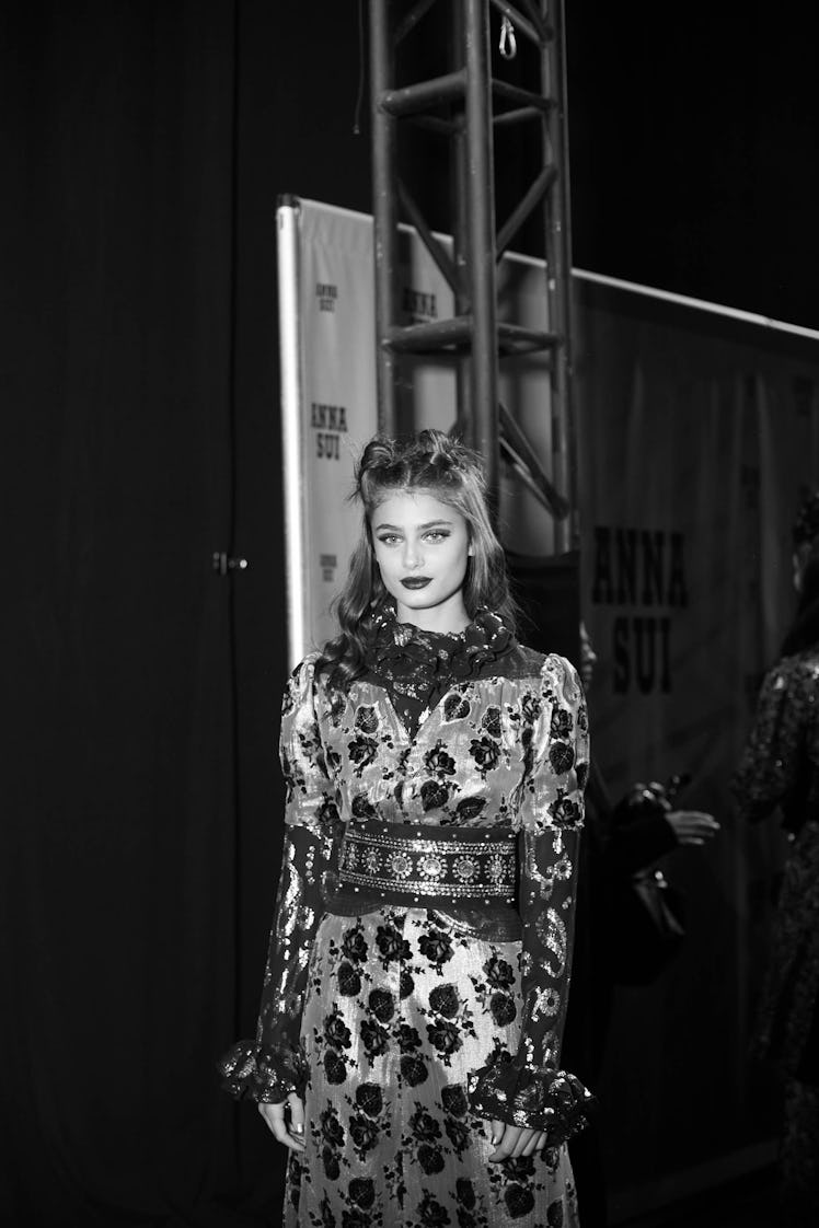Taylor Hill in a floral dress coat and a double top knot backstage at Anna Sui Fall 2017 in black an...